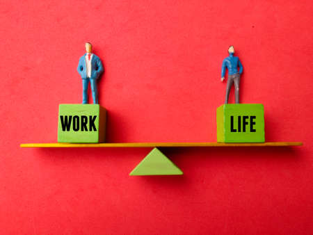 Hand holding yellow alarm clock on a blue background with copy space.の写真素材