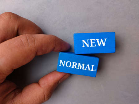 Hand holding yellow alarm clock on a blue background with copy space.の写真素材