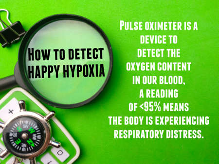 Top view magnifying glass,compass and calculator with tips How to detect HAPPY HYPOXIA on green background. Healthcare concept.の写真素材