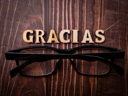 Top view glasses and wooden word with text GRACIAS on a wooden background.の写真素材