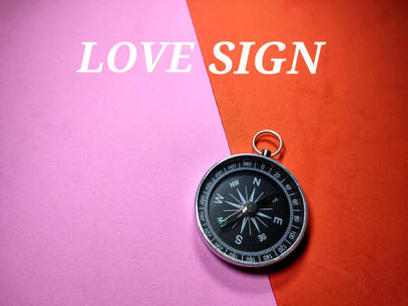 Selective focus.Word LOVE SIGN with compass on a red and pink background.Valentine concept.Shot were noise and grain.の写真素材