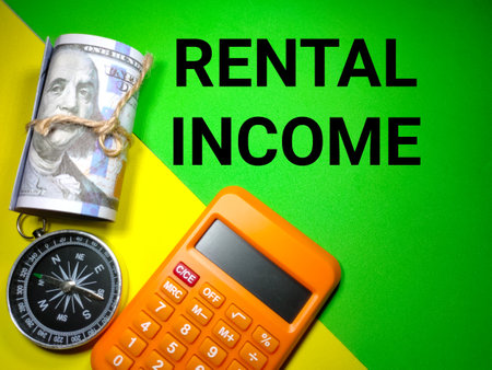 Selective focus.Banknote,compass and calculator with text RENTAL INCOME on a green and yellow background.Business concept,shot were noise and grain.の写真素材