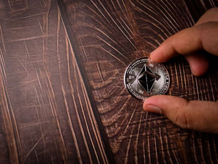 A five beautiful silver ethereum digital crypto coin on wooden table with copy space.の写真素材