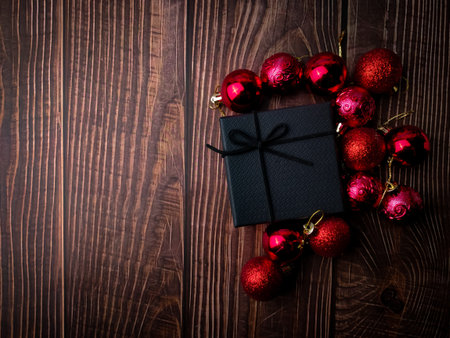 Christmas red ball and gifts box on a wooden table. Holidays christmas background. Copy space for text or design. View from above.の写真素材
