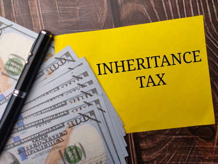 Pen,banknotes and colored paper with text INHERITANCE TAX on wooden background.の写真素材