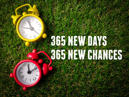 Top view alarm clock with text 365 new day and new chances on a green grass background.