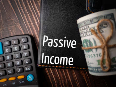 Top view banknotes,calculator,and notebook with text Passive Income on a wooden background.の写真素材