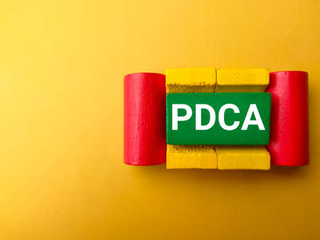 Top view colored wooden block with text PDCA on a yellow background.の写真素材
