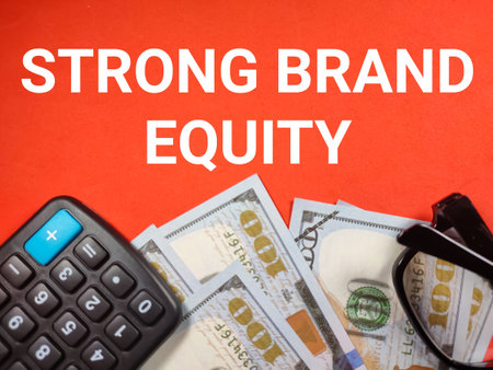 Business concept.Text BRAND LOYALTY with clock,calculator,pen and banknote on red background.