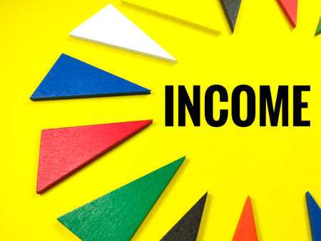 Business concept.Colorful pieces of wood on yellow background with text INCOMEの写真素材