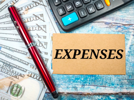 Business concept.Text EXPENSES with banknote,calculator and pen on wooden background.の写真素材