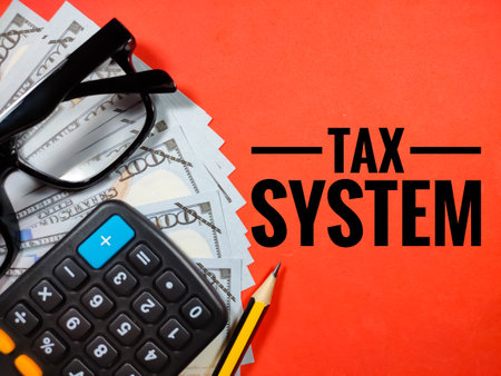 Text TAX SYSTEM on red background with glasses,pencil,calculator and banknote.Business concept.の写真素材