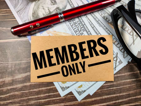 Business concept.Text MEMBERS ONLY with pen,glasses and banknote on brown wooden background.の写真素材