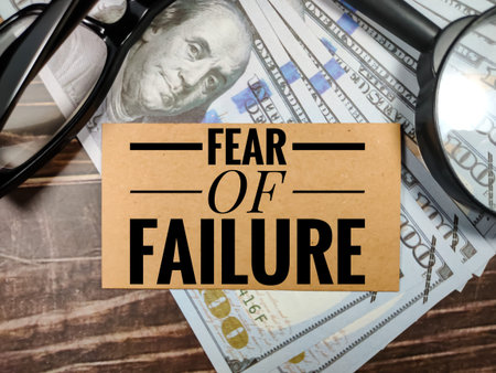 Business concept.Text FEAR OF FAILURE with magnifying glass,glasses and banknote on brown wooden...