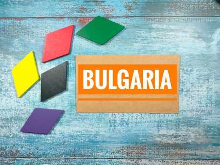 Text BULGARIA with colorful wooden jigsaw on blue wooden background.