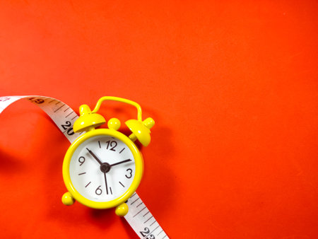 Measuring tape and clock on red background with copy space.