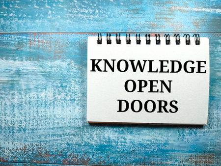 Notebook with text KNOWLEDGE OPEN DOORS on blue wooden background.の写真素材