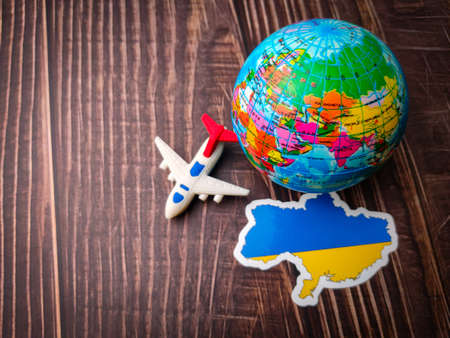 Top view ukraine flay,toys plane and earth globe on wooden background.の写真素材