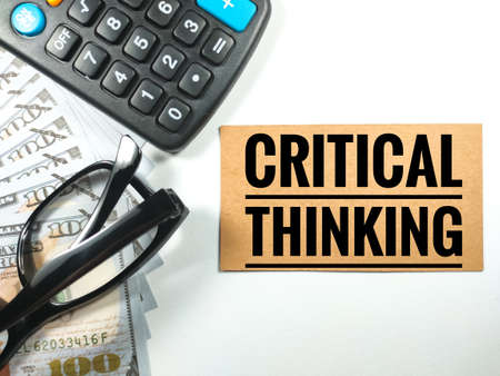Business concept.Text CRITICAL THINKING with calculator,glasses and banknote on white background.の写真素材