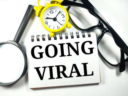 Business and finance concept.Text GOING VIRAL with magnifying glass,clock and glasses on white background.の写真素材