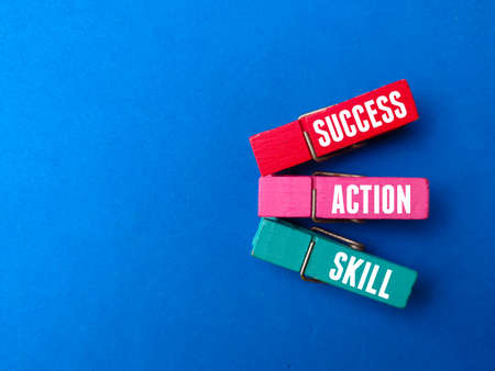 Top view wooden clips with text SUCCESS,ACTION,SKILL on blue background.の写真素材