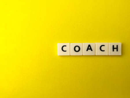 Top view toys word with text COACH on yellow background with copy space.の写真素材