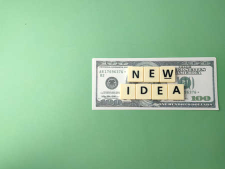 Top view toys word and banknotes with text NEW IDEA on green background.の写真素材
