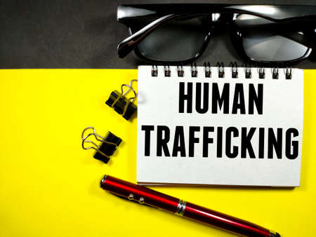 Business concept. Notebook with text HUMAN TRAFFICKING  on black and yellow backgroundの写真素材