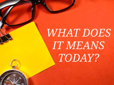 Education concept.Text WHAT DOES IT MEANS TODAY? with compass and glasses on red background.の写真素材