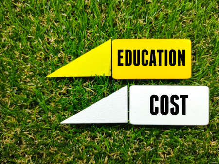 Colorful wooden board with text EDUCATION COST on grass background.の写真素材