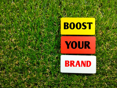 Business concept.Text BOOST YOUR BRAND on wooden board with grass background.