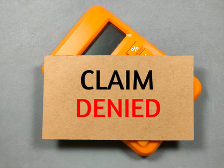 Text CLAIM DENIED on brown card with calculator on gray background.