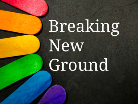Colorful wooden stick with text BREAKING NEW GROUND on black background.の写真素材