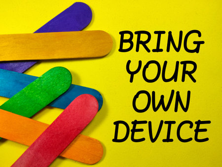 Text BRING YOUR OWN DEVICE with colorful wooden stick on yellow background.