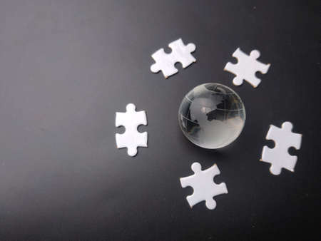 Earth crystal ball with white jigsaw puzzle on a black background.の写真素材