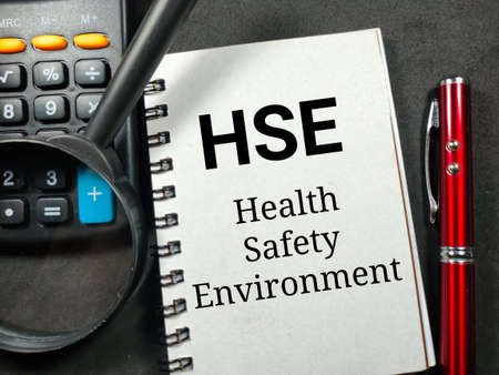 Business concept.Text HSE Health Safety Enviroment writing on notebook with magnifying glass,pen and calculator on a black background.の写真素材
