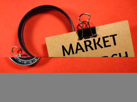 Business concept.Text MARKET RESEARCH writing on brown card with compass and magnifying glass on a red background.の写真素材