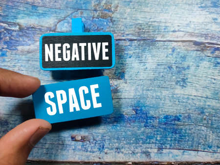 Text NEGATIVE SPACE writing on colored wooden board on a blue wooden background. Trending photos concept.の写真素材