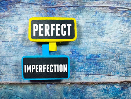 Text PERFECT IMPERFECTION writing on colored wooden board on a blue wooden background. Trending photos concept.の写真素材