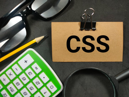 Text CSS (Cascading Style Sheet) writing on brown card with magnifying glass, pencil,calculator and...