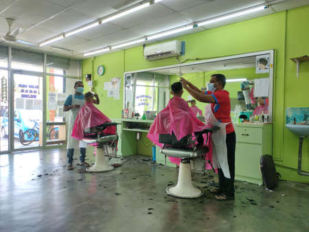 Malaysia, 20 March 2022: Two children are having their hair cut in conjunction with the opening of the school earlier this year.のeditorial素材