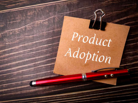 Pen and brown card with text Product Adoption on wooden background.の写真素材