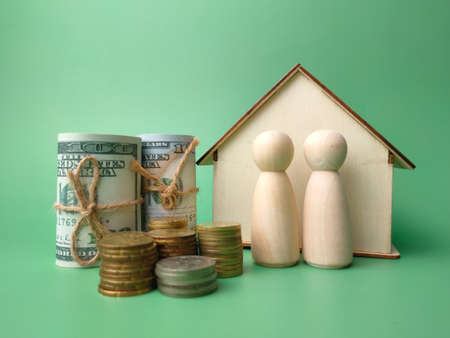 Coins,banknotes,wooden figures and wooden house on a green background.の写真素材