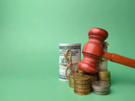 Wooden gavel,banknotes and coins on a green background with copy space.の写真素材