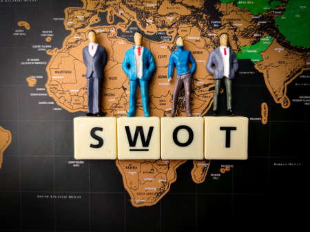 Top view miniature people and toys word with text SWOT on a world map backgroundの写真素材