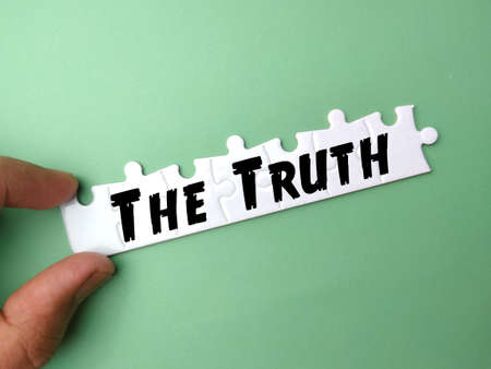 Hand holding white puzzle with text The Truth on green background.の写真素材