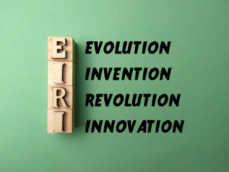 wooden block and word with word EVOLUTION INVENTION REVOLUTION INNOVATION on green background.の写真素材
