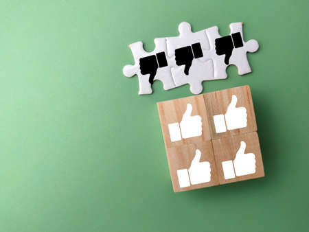 White puzzle and wooden cubes with good and bad hand icons. Thump up and thump down.の写真素材