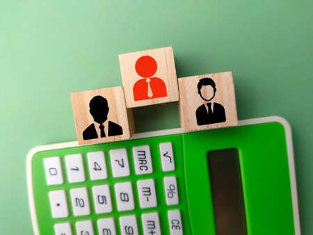Wooden block and calculator with an old employee icon and a new employee is included. business conceptの写真素材