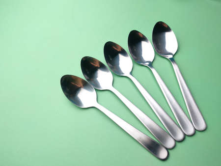 Stainless steel spoon arranged on a green background.の写真素材